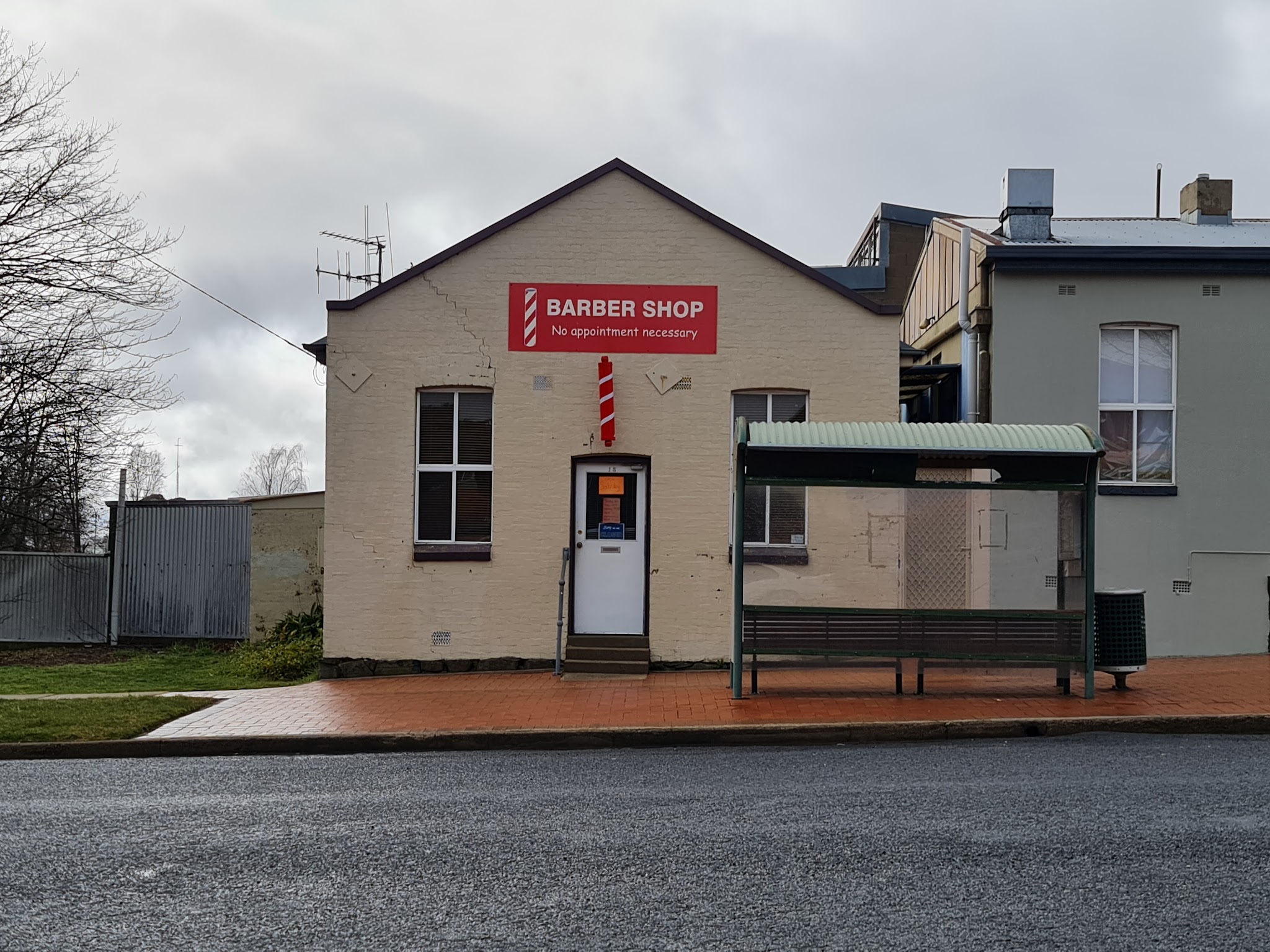 The Oberon Barbershop shopfront: a cream brick building with a red Barber Shop sign and barber pole on Fleming Street